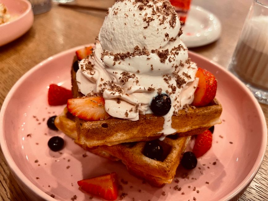 Tasty waffles topped with whipped cream, ice cream, strawberries, and blueberries.