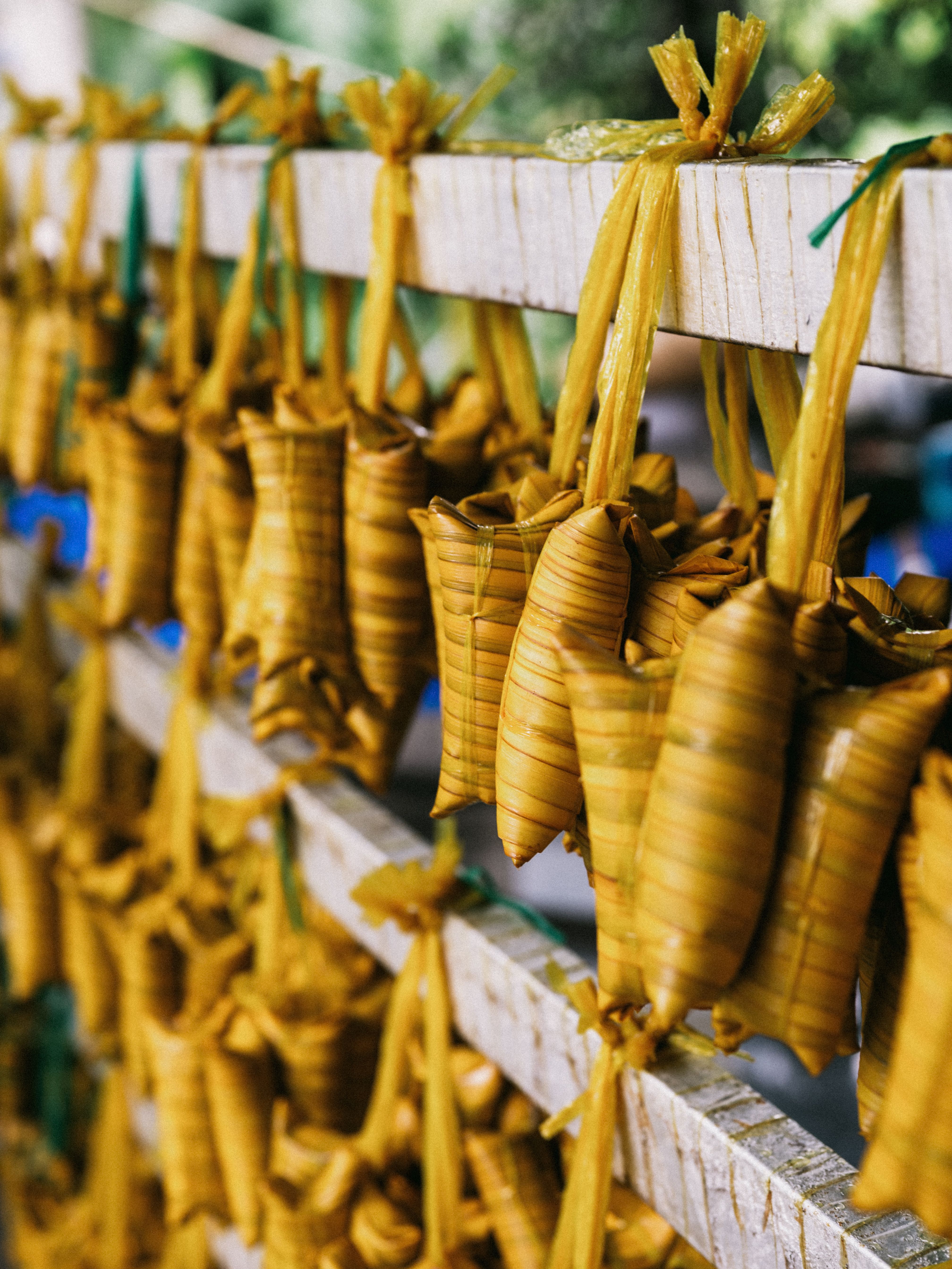 Close-up of traditional Asian leaf-wrapped snacks drying on a sunny day, showcasing craftsmanship and textures.