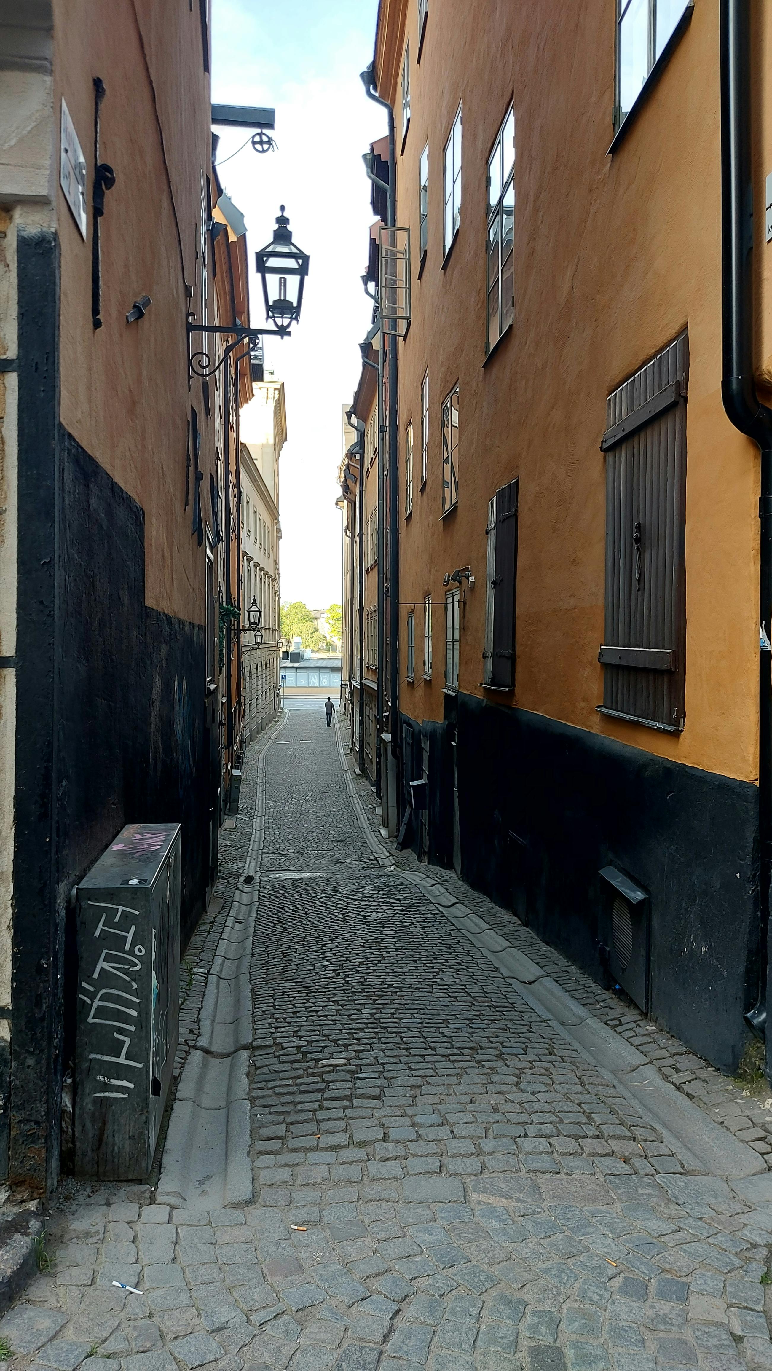 Explore a quaint, narrow cobblestone alley in Stockholm's historic Gamla Stan district.