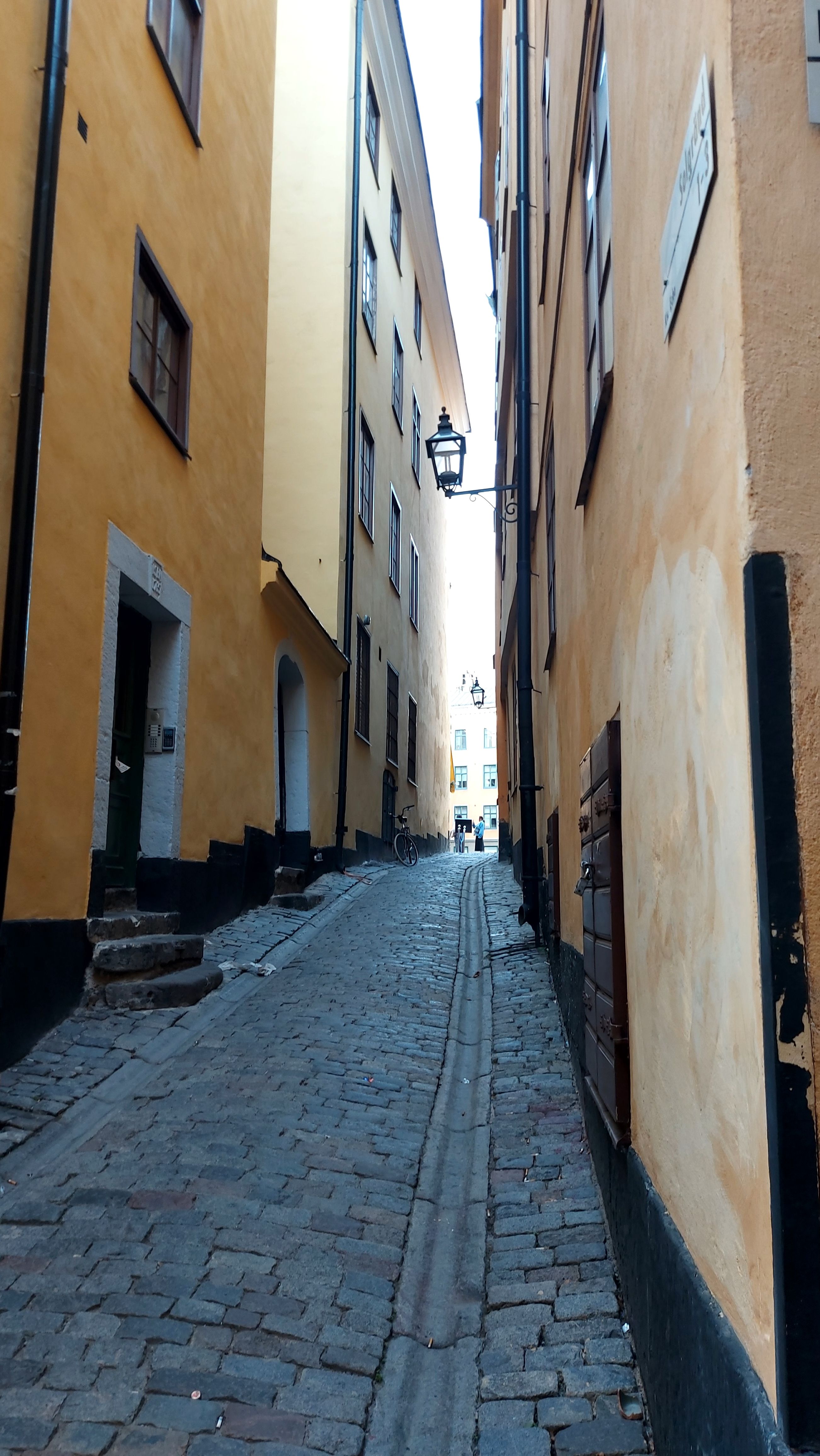 Explore a charming cobblestone alleyway in an old European town with yellow walls and classic architecture.