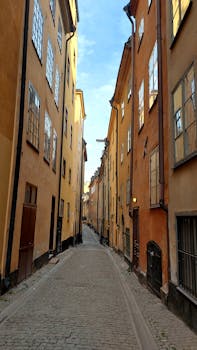 Explore a historic cobblestone street lined with colorful tall buildings in Stockholm's old town.