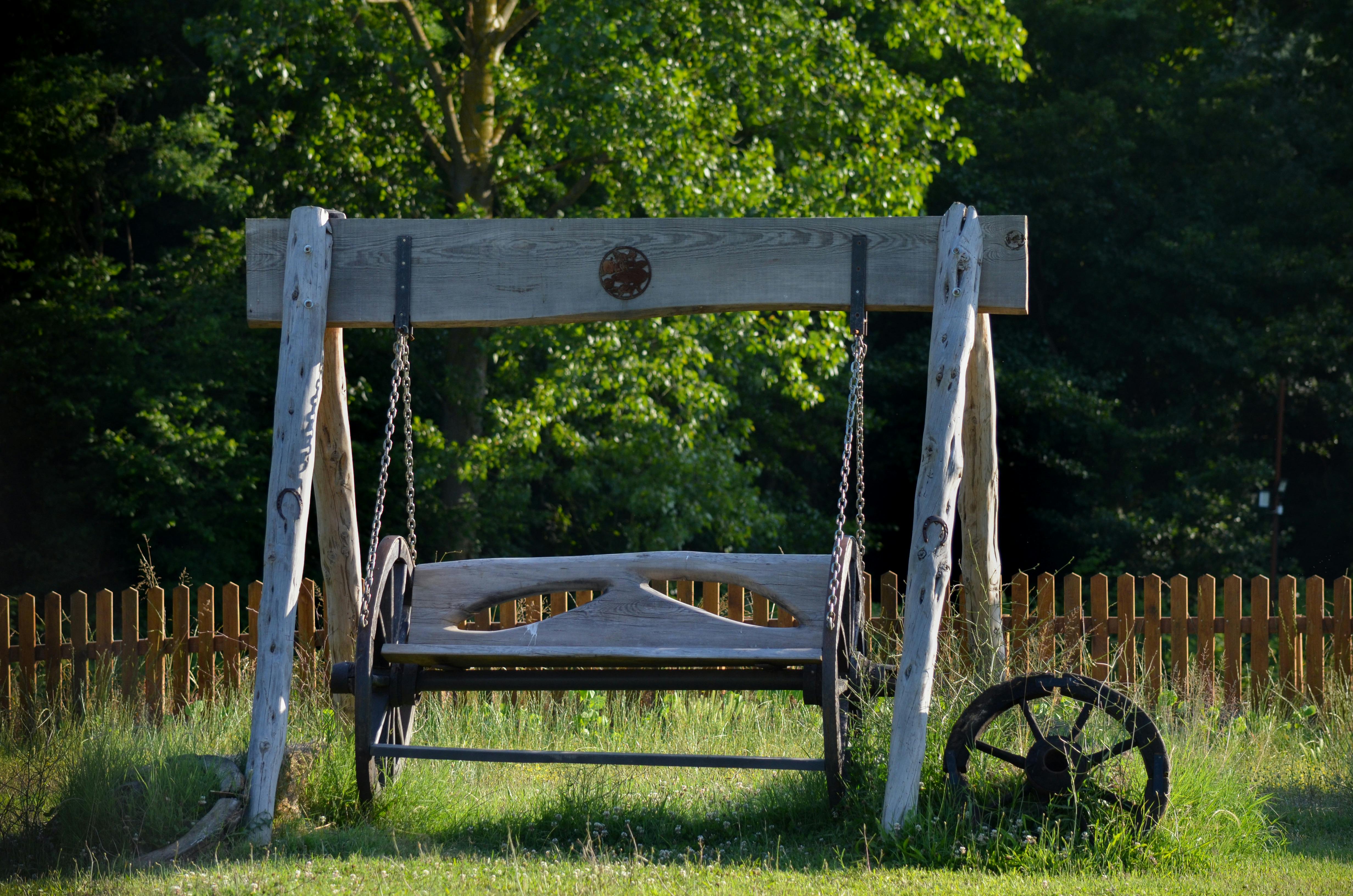 Charming wooden swing in a lush green backyard, perfect for relaxation.