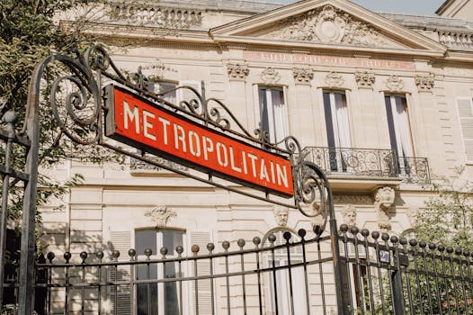 Elegant Metropolitain sign with traditional Parisian architecture in the background, under clear skies.