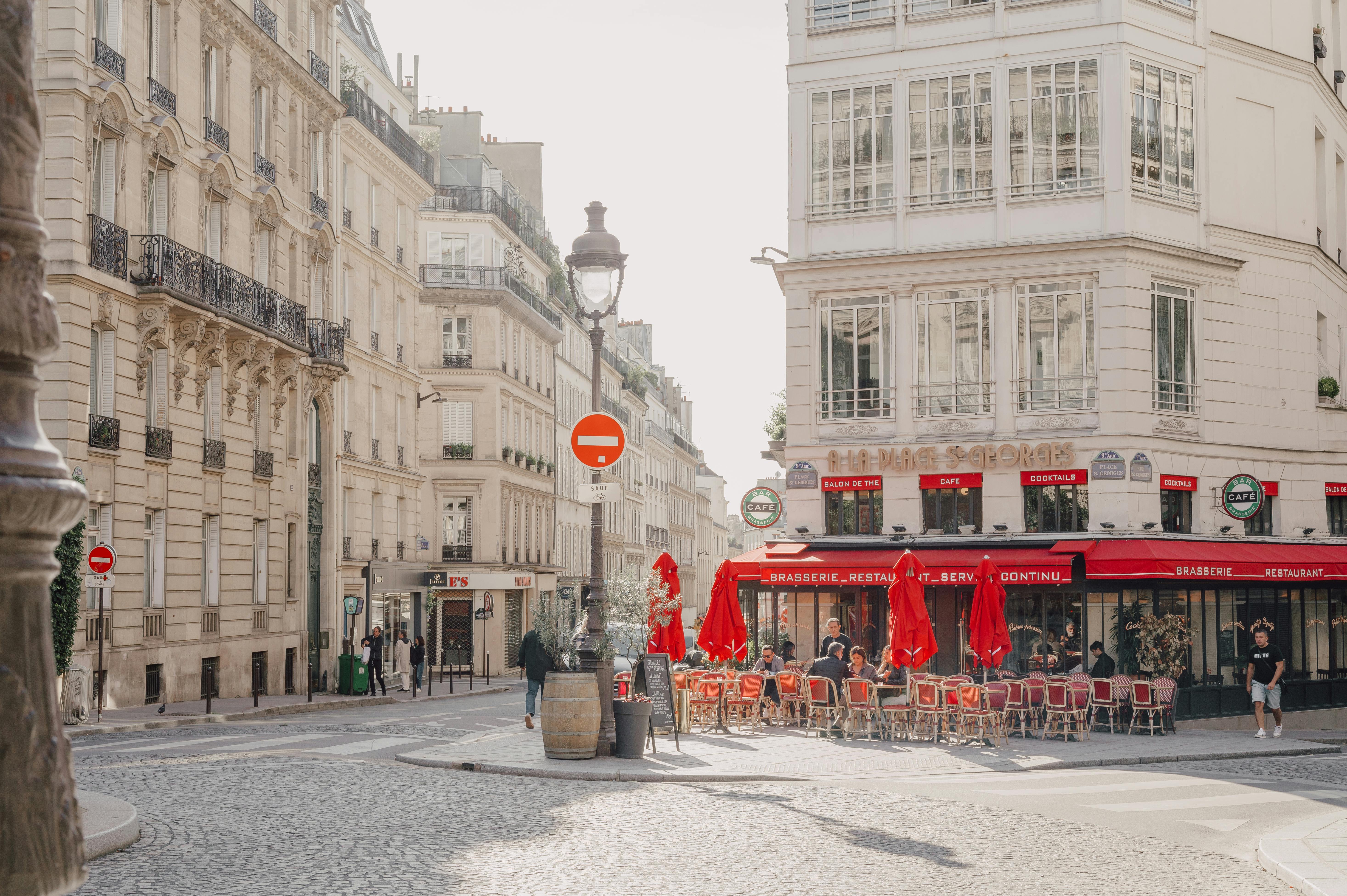 Cozy cafe on a charming street corner in Paris with classic architecture, captured in bright daylight.