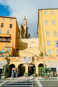 Colorful buildings line a street with St. Michel's Basilica in sunny Menton, France.
