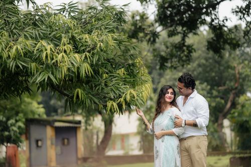 Free A couple shares a tender moment outdoors beneath a lush green tree on a sunny day. Stock Photo