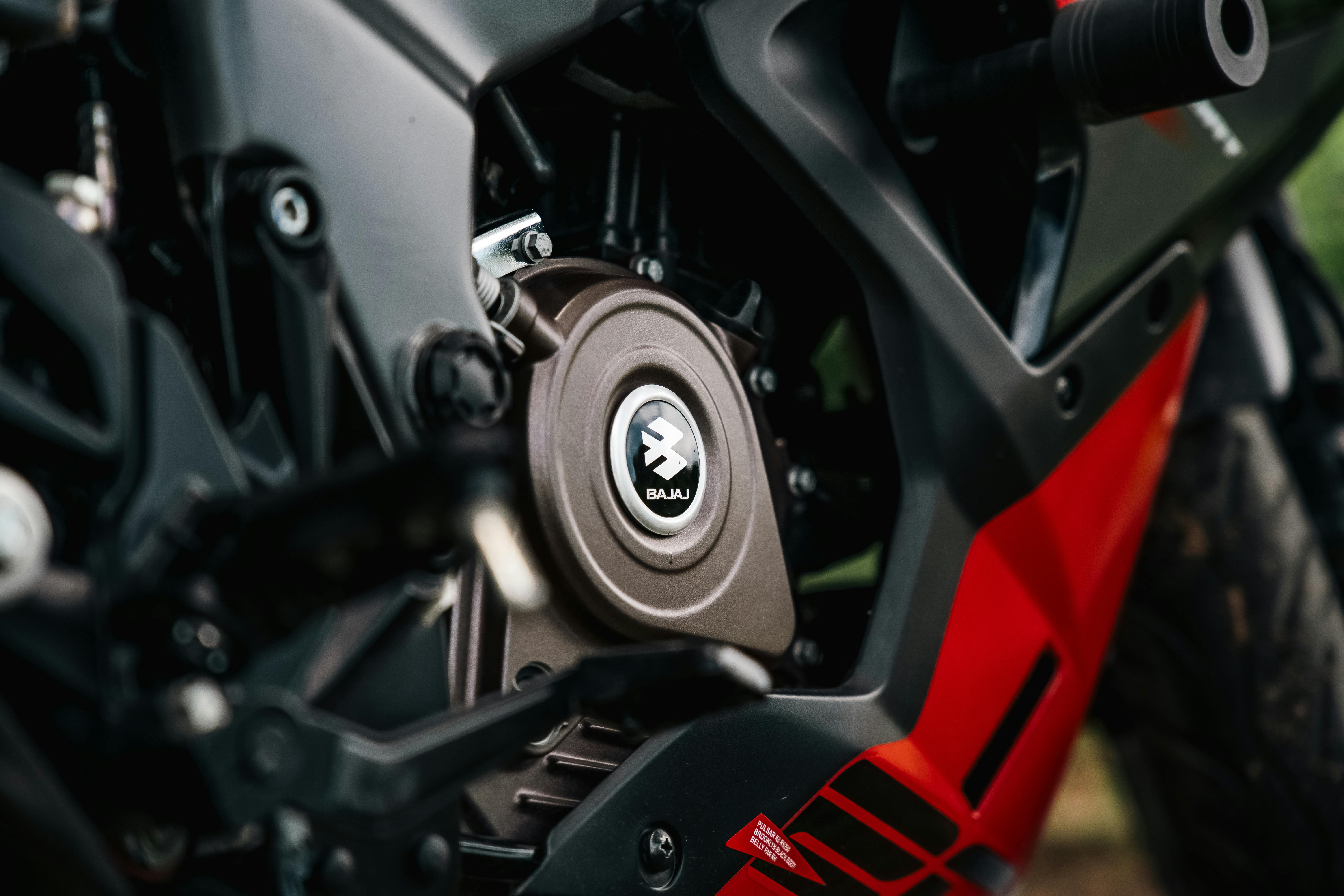Detailed close-up view of a Bajaj motorcycle engine with striking red and black color scheme.