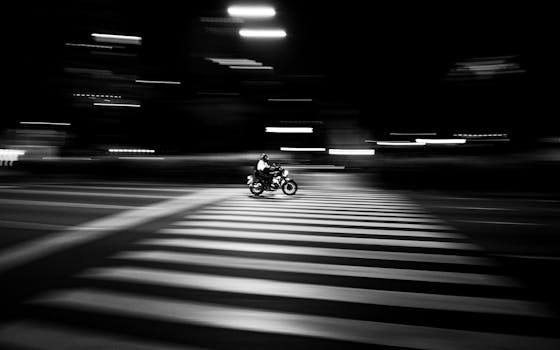 Black and white image of a motorcycle speeding across a zebra crossing at night in Buenos Aires.