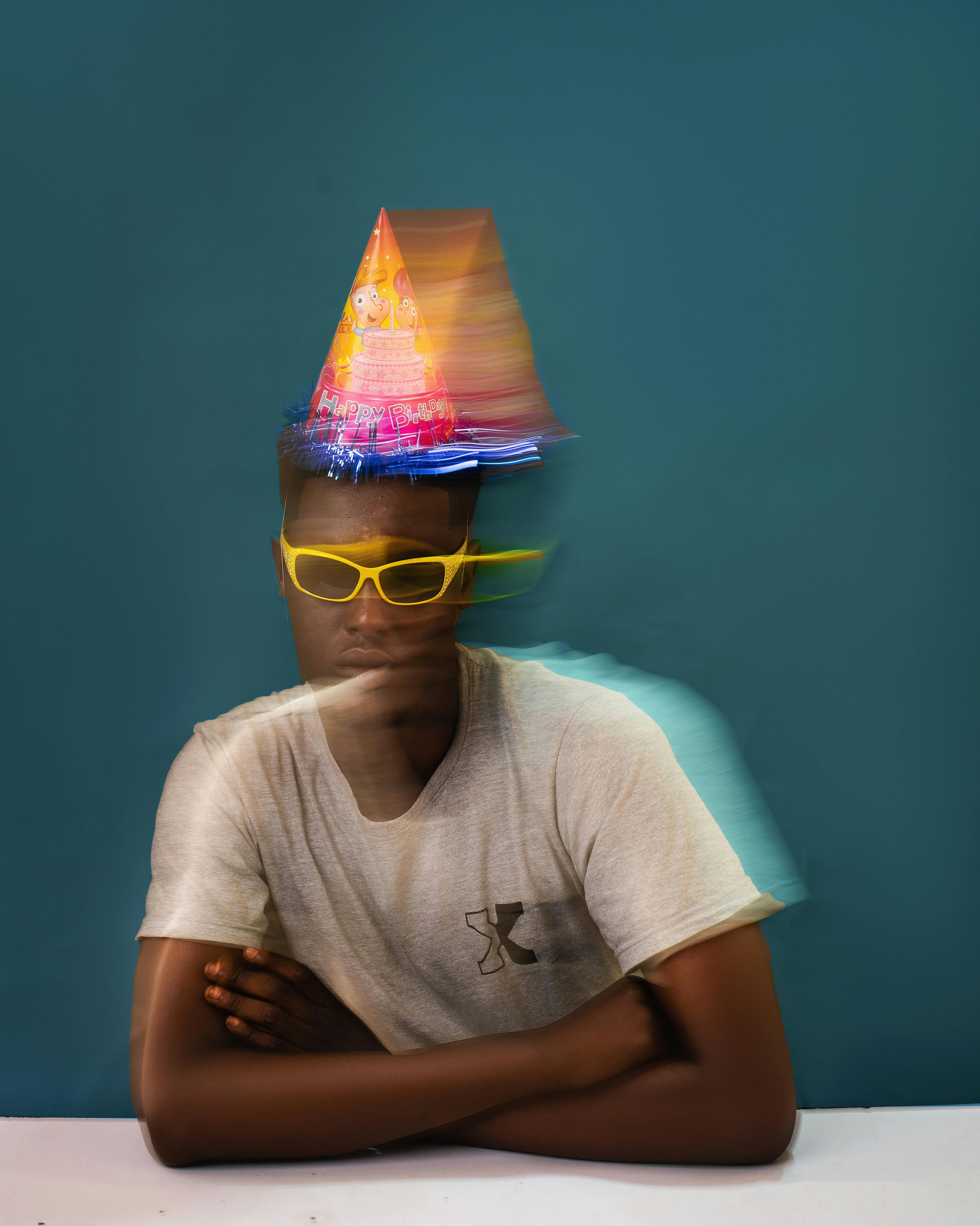 Creative portrait of a person wearing a party hat and glasses, showcasing blurred motion effect.