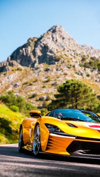 A striking yellow sports car driving on a picturesque road with stunning mountain views.
