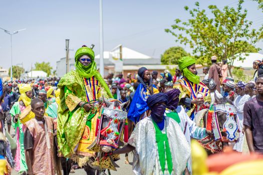 Vibrant festival parade with people in traditional attire riding decorated horses.
