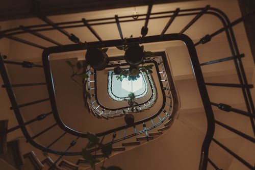 Free Hypnotic upward view of a spiral staircase with wrought iron railings and elegant lighting. Stock Photo