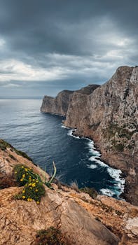 Majestic cliffs overlooking the ocean under a moody sky in Ibiza, Spain.