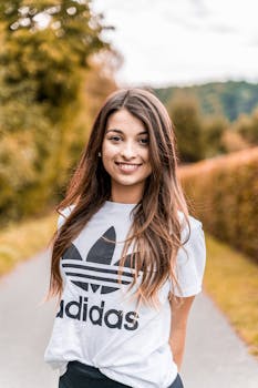 一位年轻女子穿着带徽标的白衬衫，在户外微笑着摆姿势