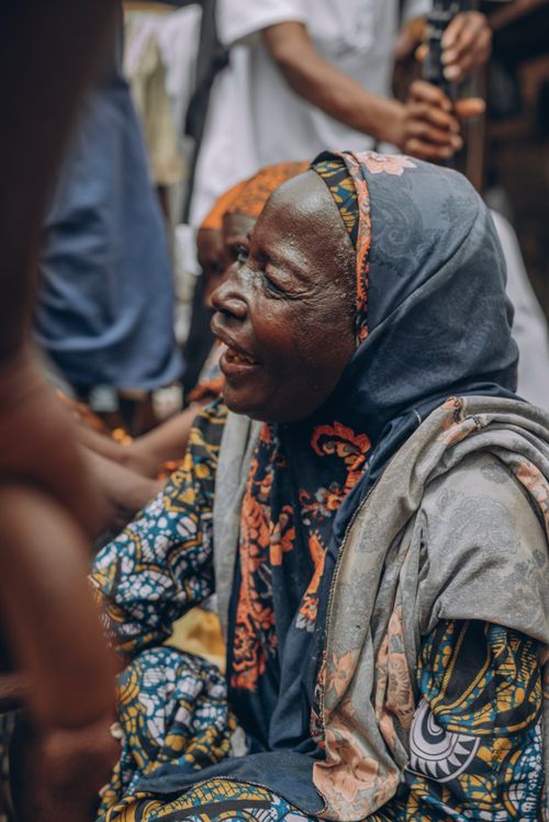 Free Joyful elderly woman in colorful traditional attire, captured outdoors among people. Stock Photo