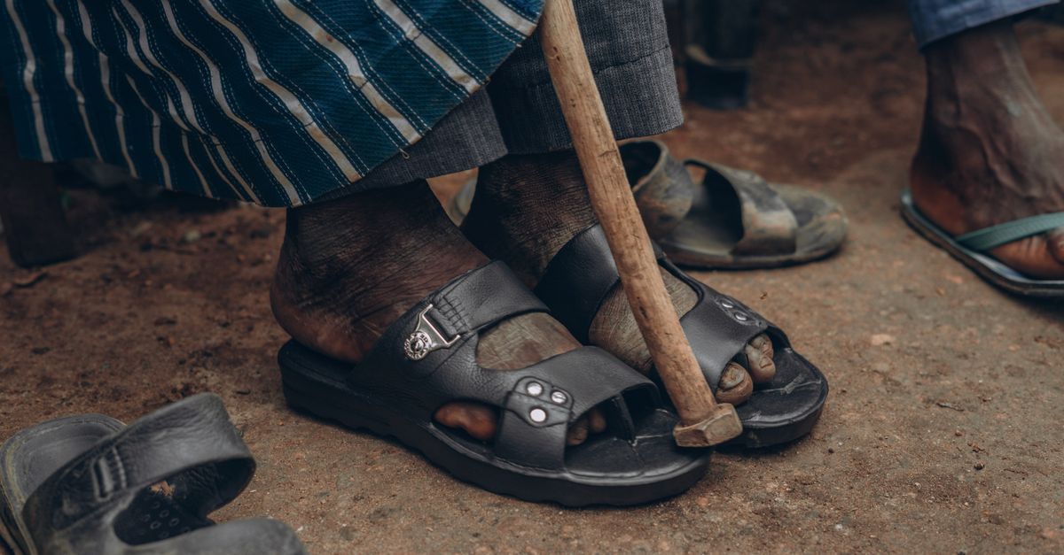Close-up of feet in sandals with a walking cane, embodying cultural attire and lifestyle.