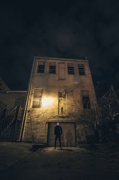 夜晚，一个蒙面身影笼罩在废弃建筑周围，营造出一种神秘而令人毛骨悚然的气氛