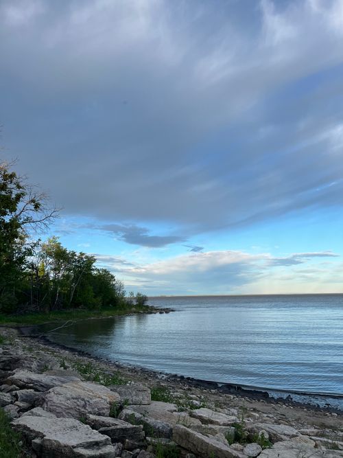 Free Peaceful lakeside view with dramatic clouds and tranquil water, perfect for relaxation themes. Stock Photo