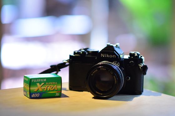 Nikon SLR next to a roll of Superia