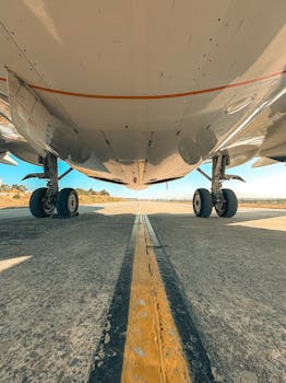 Detailed view of airplane wheels and undercarriage on a runway during a clear day.