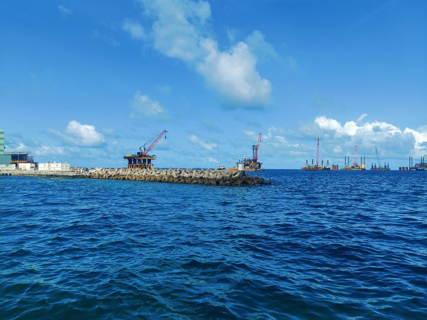 An offshore industrial platform with cranes in Maldives under a clear blue sky.