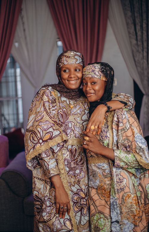 Free Two women in colorful traditional African attire embracing and smiling indoors, conveying warmth and culture. Stock Photo