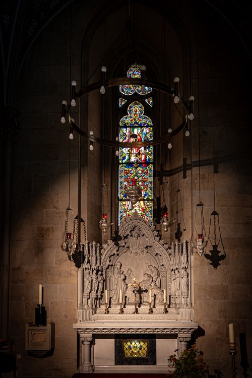 Free Gothic church altar with intricate carvings and colorful stained glass window in dramatic lighting. Stock Photo