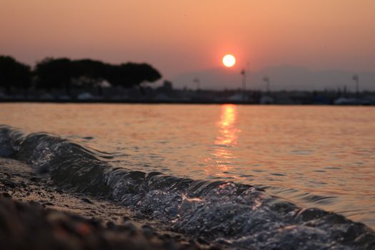 Captivating sunset view over Lake Garda with gentle waves and silhouettes.