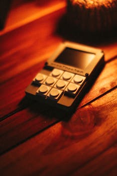 A vintage calculator placed on a wooden desk illuminated by warm, ambient lighting.