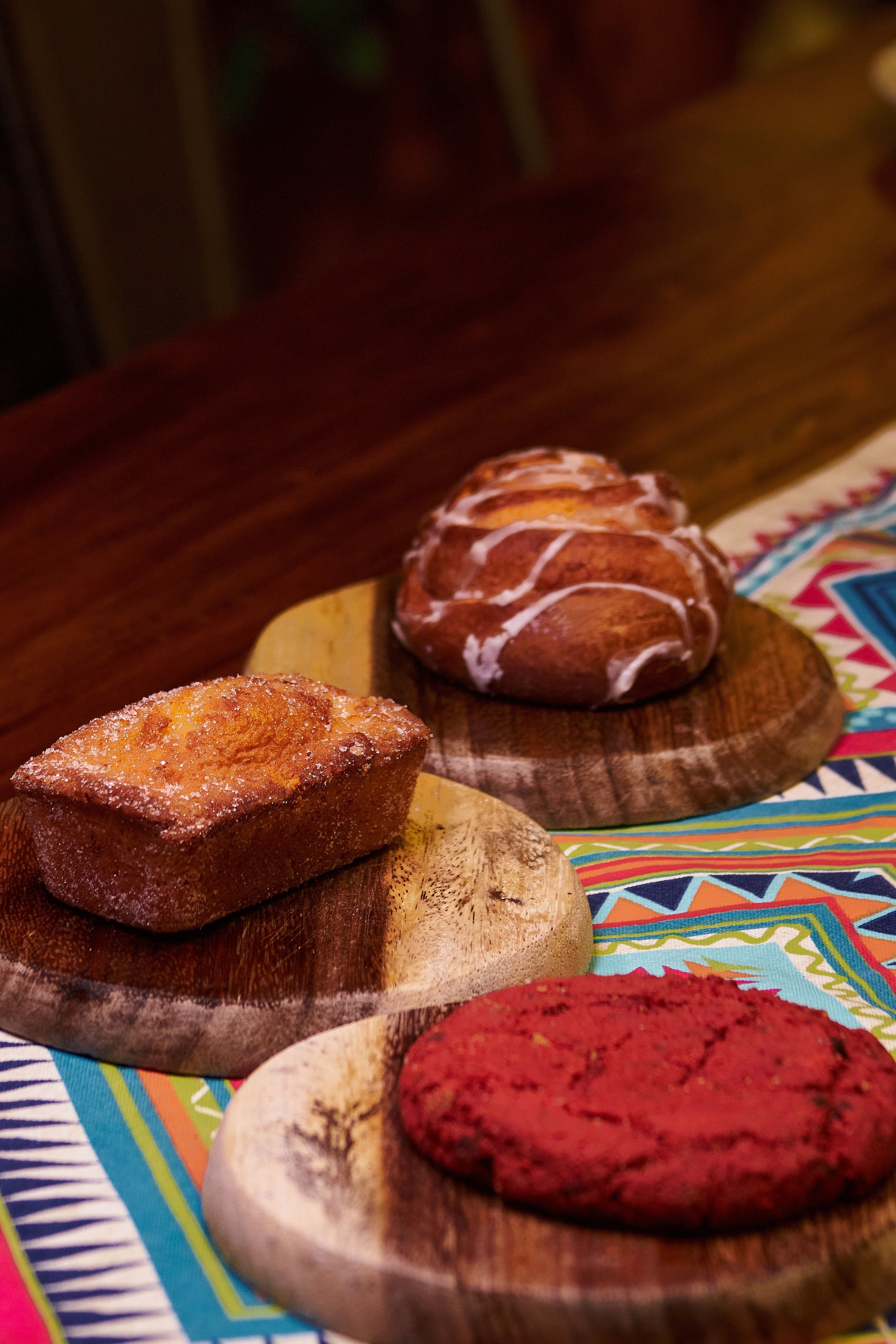 Delicious artisan pastries on rustic wooden boards showcasing vibrant Mexican textiles.