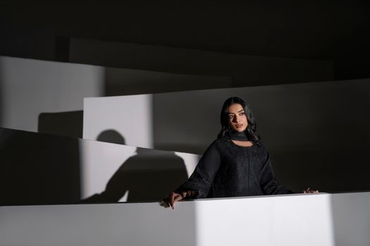 Stylish portrait of a woman in black eastern dress, creating dramatic shadows in Lahore, Pakistan.
