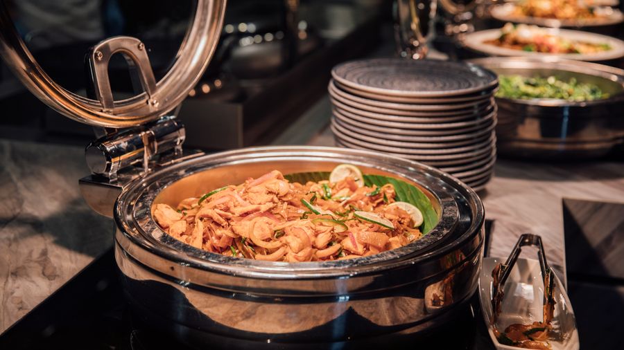 Buffet style chicken curry in a chafing dish with lime and veggies