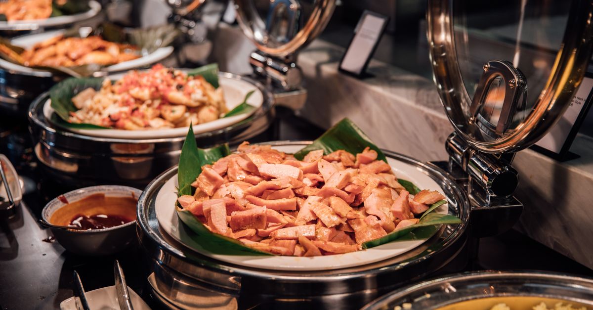Um buffet suntuoso com carnes variadas e arroz servido em um ambiente luxuoso.