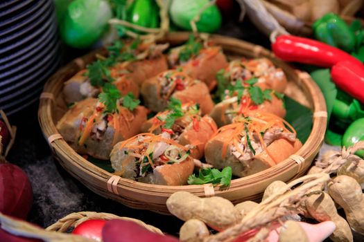 Close-up of a Vietnamese Banh Mi sandwich platter surrounded by fresh vegetables.