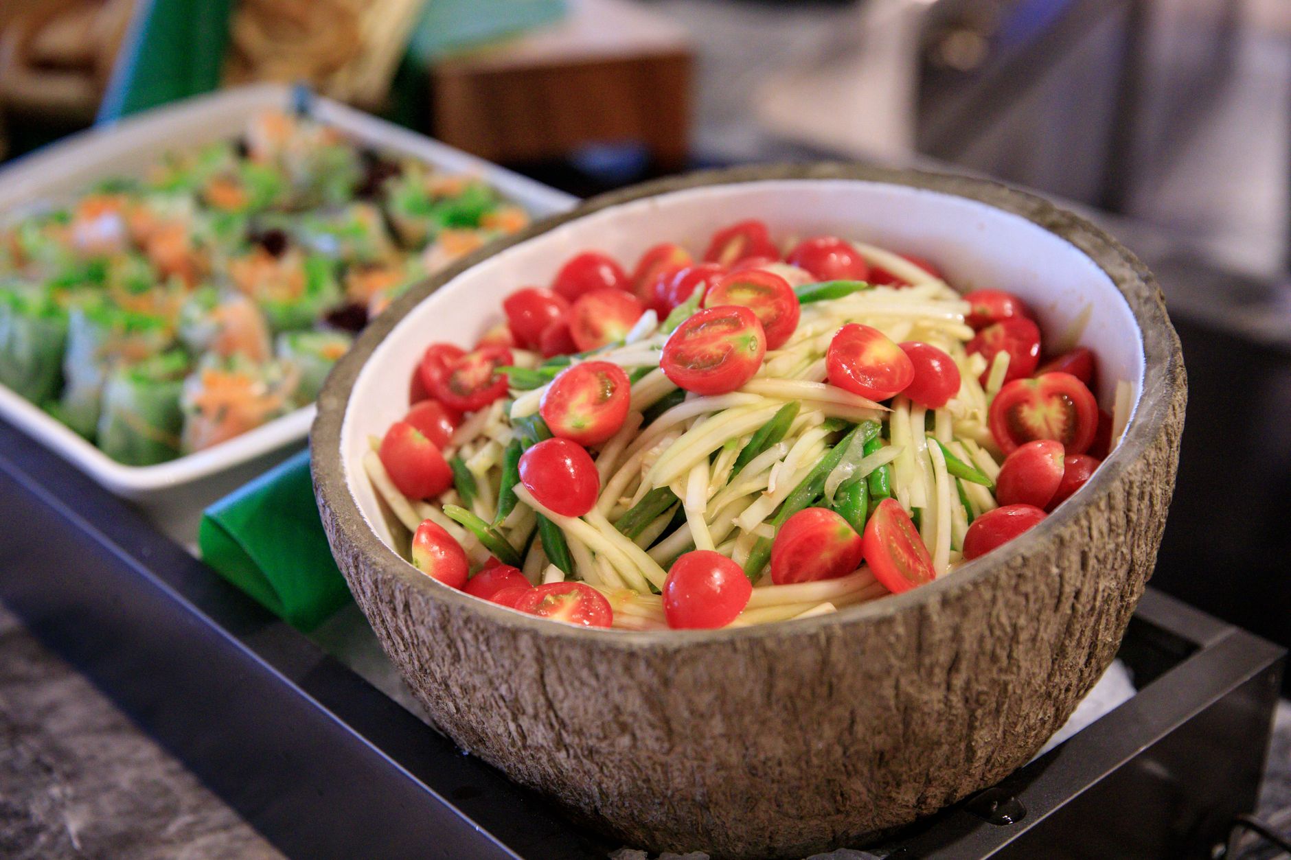 A vibrant papaya salad with cherry tomatoes in a coconut bowl, perfect for Thai cuisine lovers.