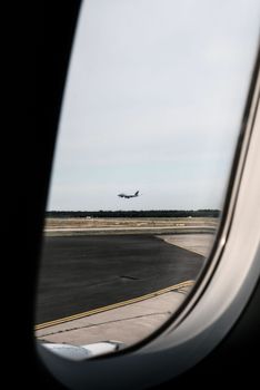 View of a commercial airplane landing on the runway, captured from a plane window.