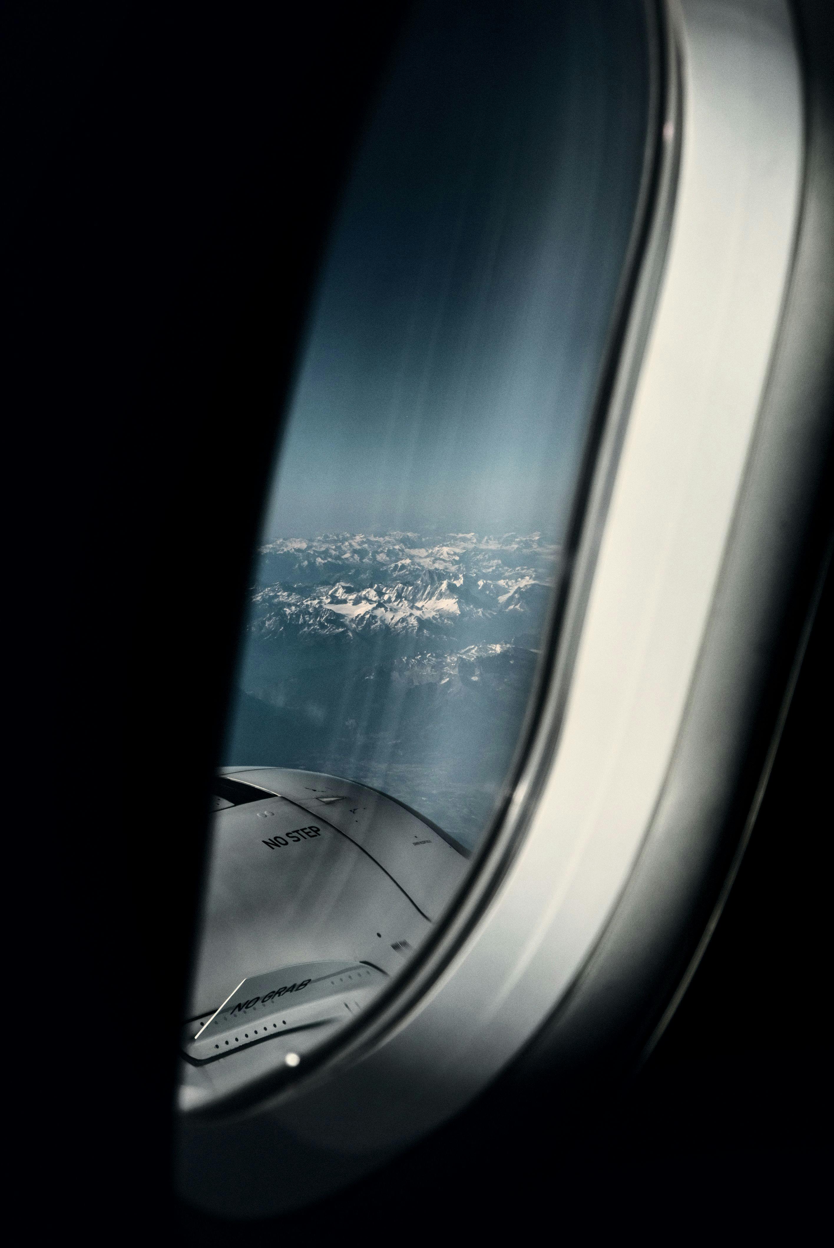 Free A breathtaking view of snow-capped mountains from an airplane window during flight. Stock Photo