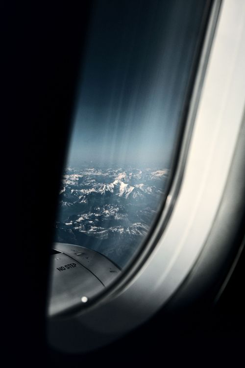 Free Breathtaking aerial view of snowy mountain peaks through an aircraft window in clear skies. Stock Photo