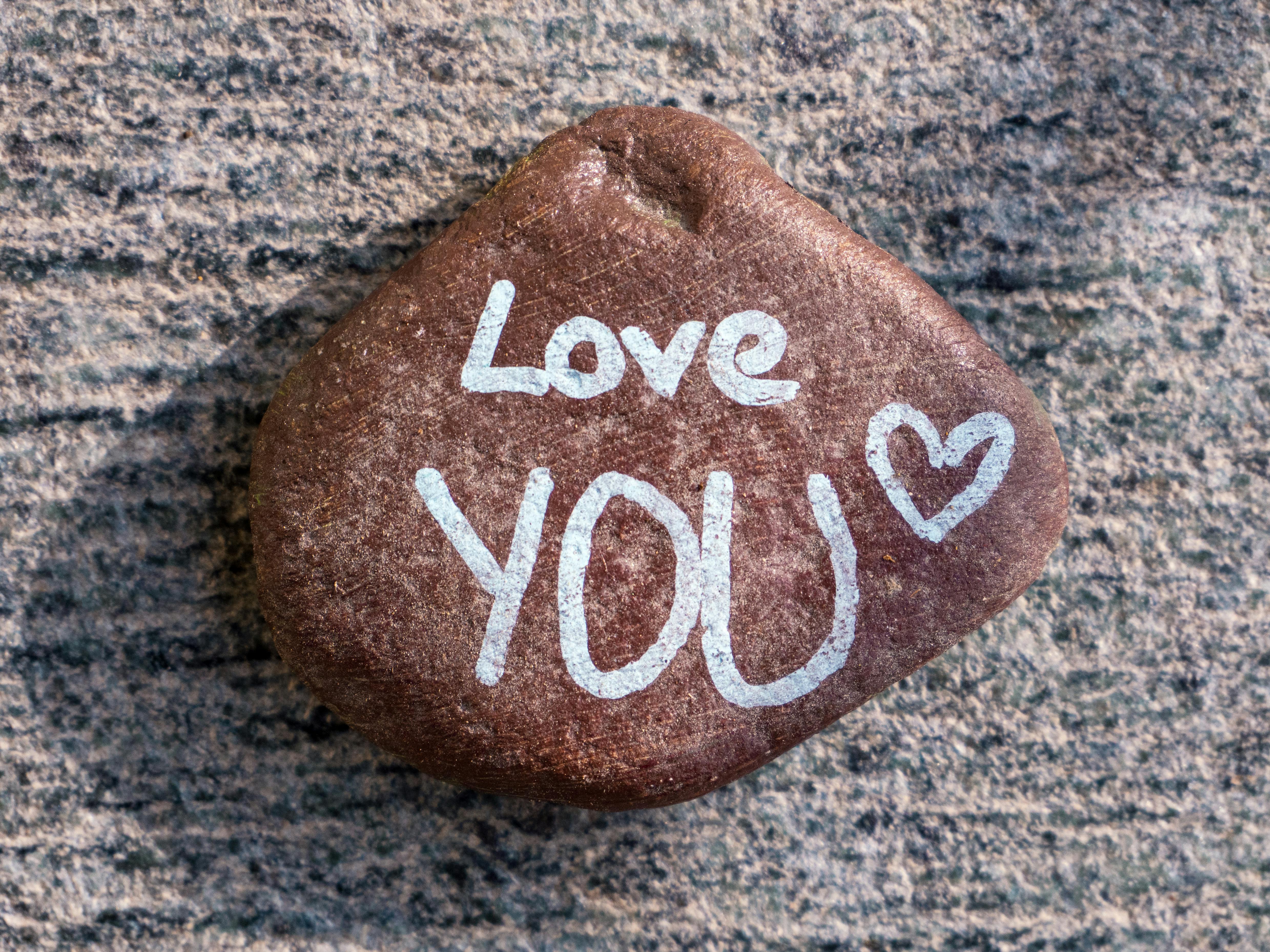 A smooth stone with 'Love YOU' written in white, creating a warm, affectionate vibe.