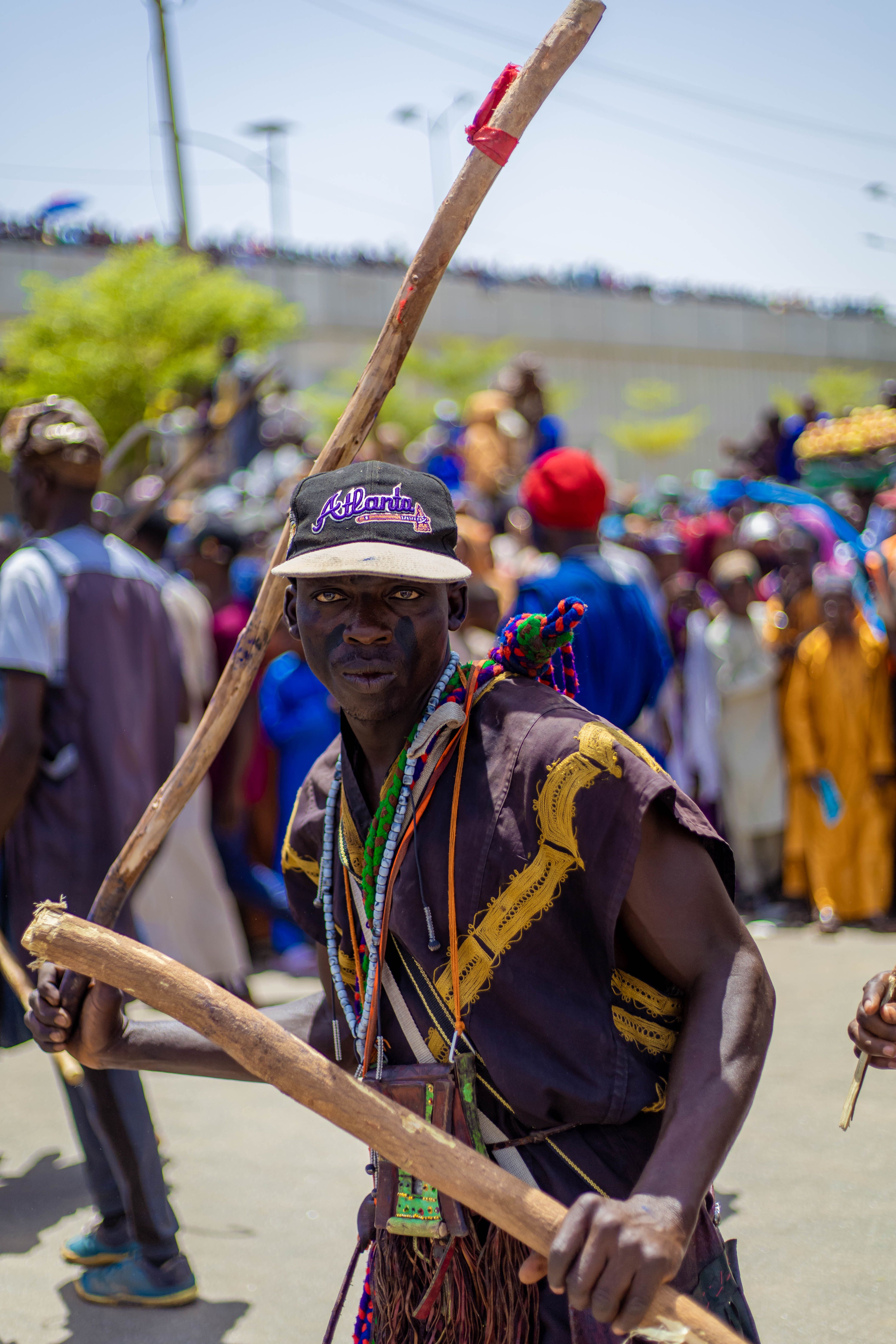 Vibrant scene of an African cultural festival with a traditional dancer holding sticks.