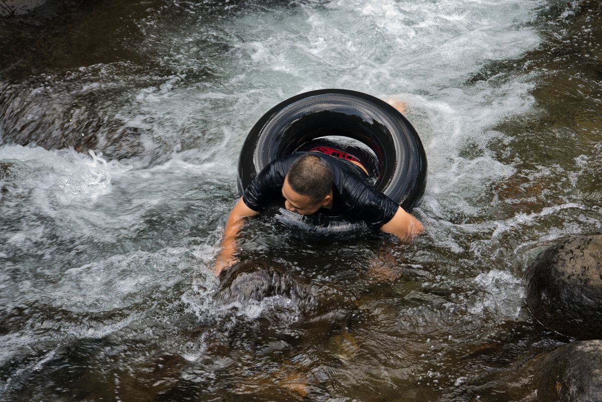An adult man enjoys tubing down a rocky river, embracing outdoor adventure and n