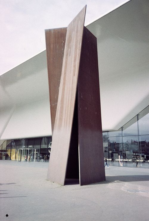 Free Abstract metal sculpture outside a modern building, showcasing contemporary art and architecture. Stock Photo