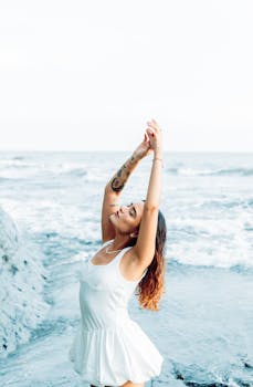 A woman joyfully embraces the ocean breeze on a sunny day in Bahia Malaga, Colombia.