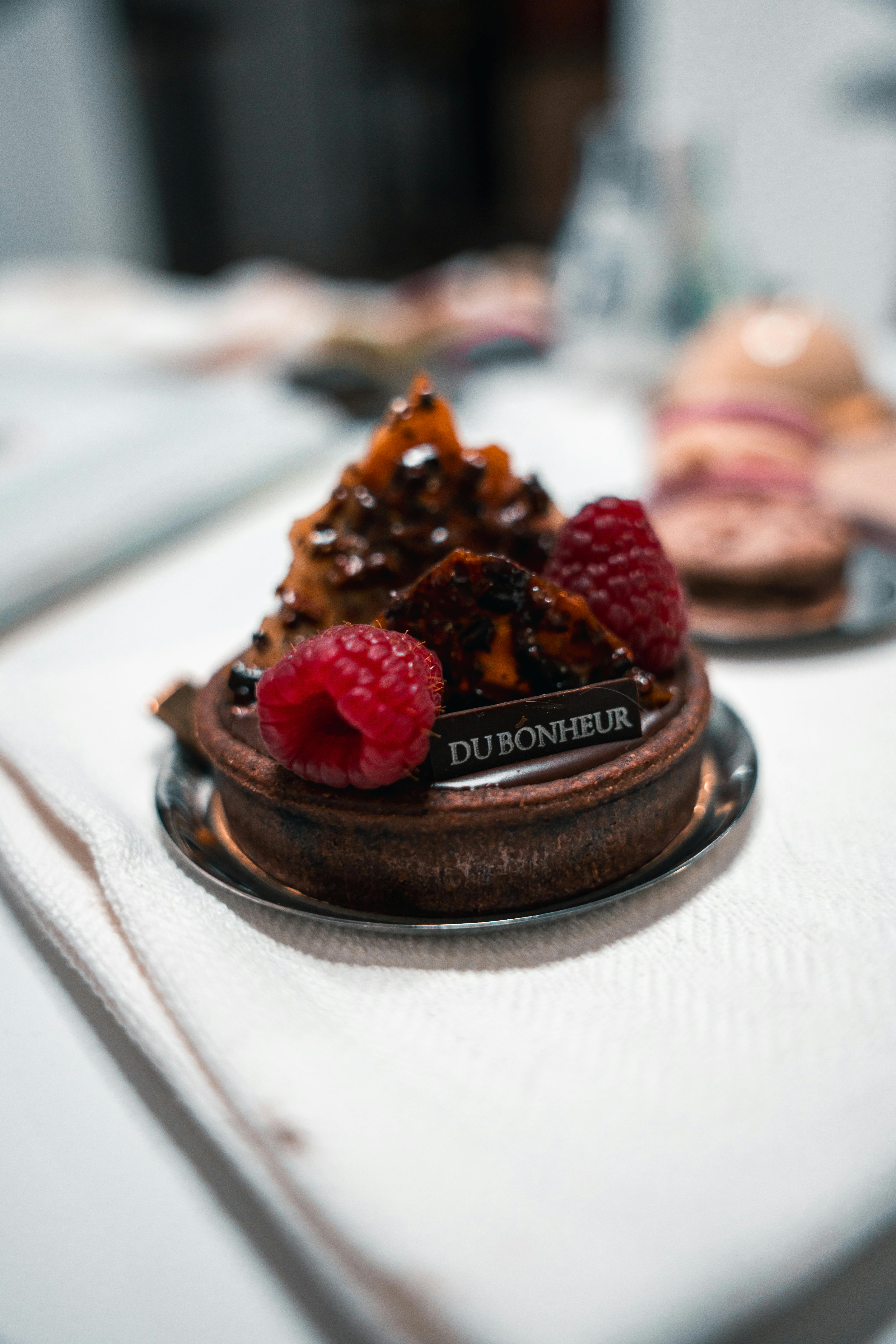 Close-up of a raspberry tart with caramel and chocolate, showcasing French pastry elegance in Berlin.