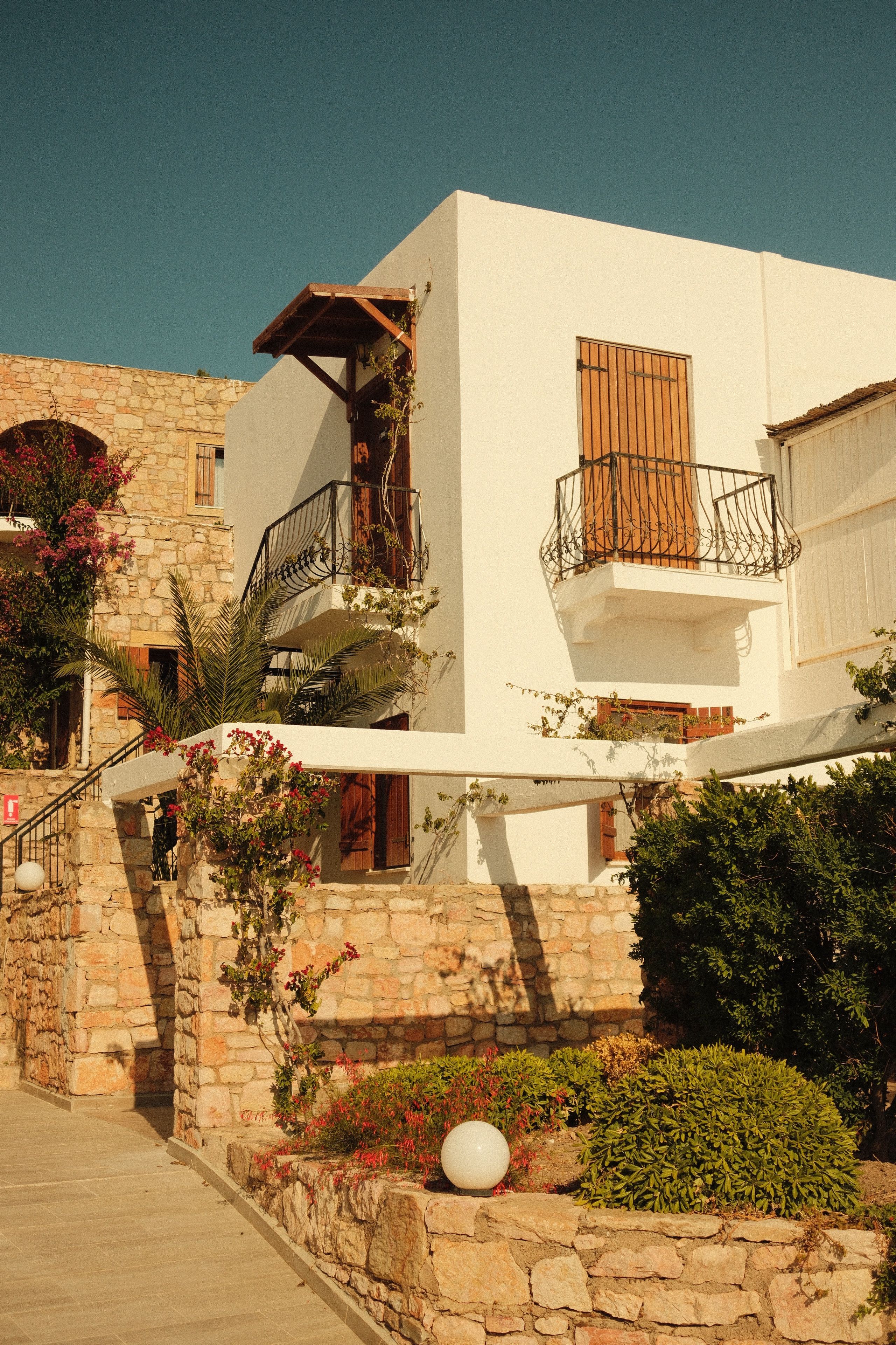 Classic Mediterranean house with stone walls and garden in warm summer light.