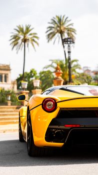 Yellow sports car parked near palm trees in sunny city setting, capturing vibrant luxury.