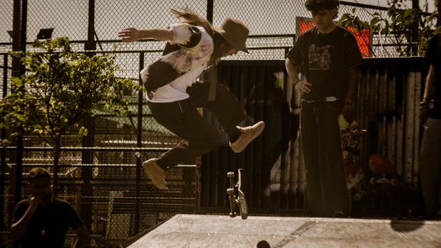 A skateboarder performs a trick mid-air in an urban park setting.. skateboarder, performs, trick