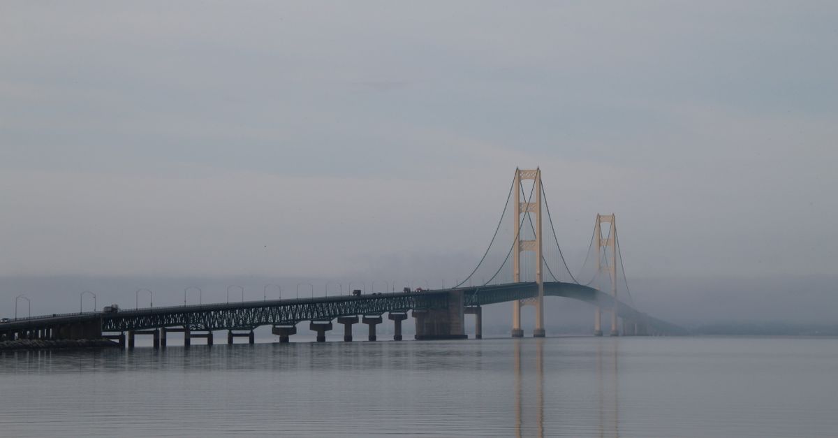 A serene view of the Mackinac Bridge shrouded in mist during the day.