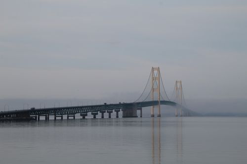 Free A serene view of the Mackinac Bridge shrouded in mist during the day. Stock Photo