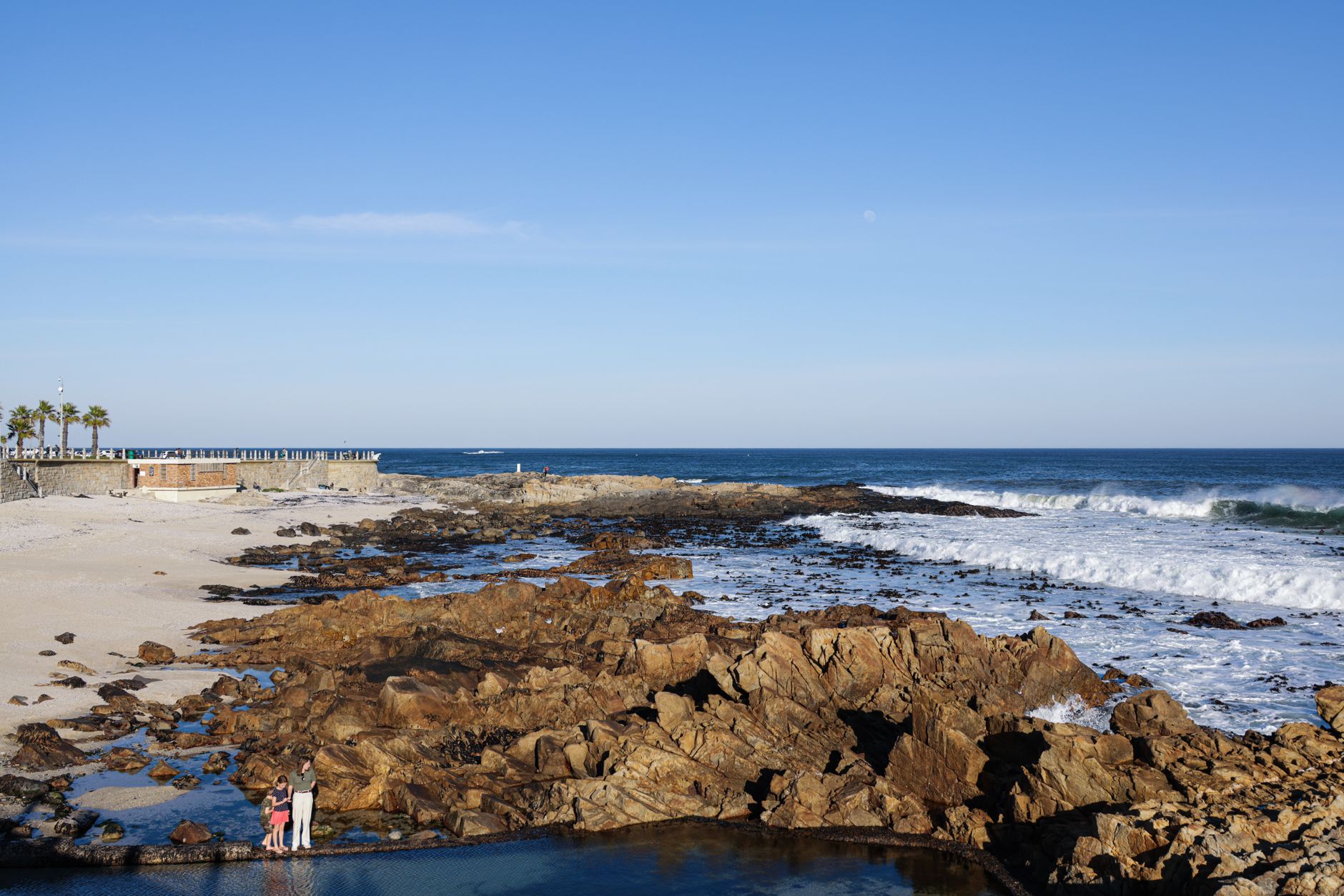Sunny day at a rocky beach with ocean waves on South Africa's coastline.